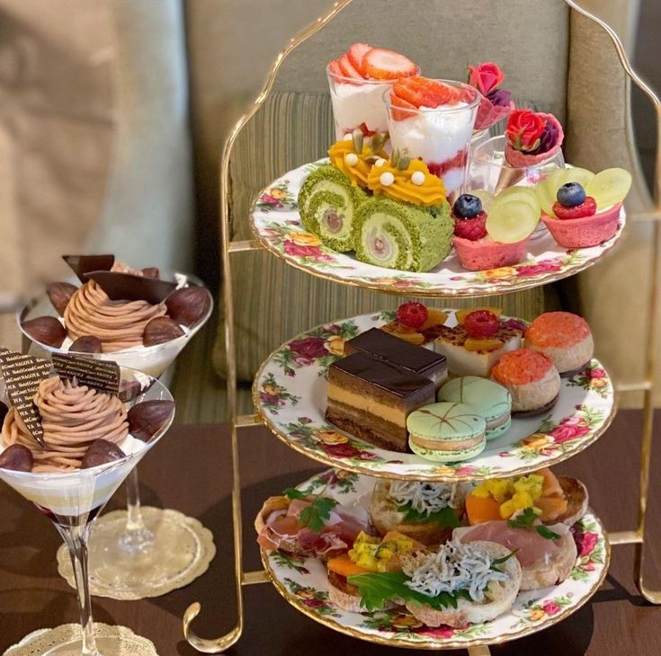 Colorful english-style tea time platter with mini cakes, macarons, savory toasts and two parfaits on the side